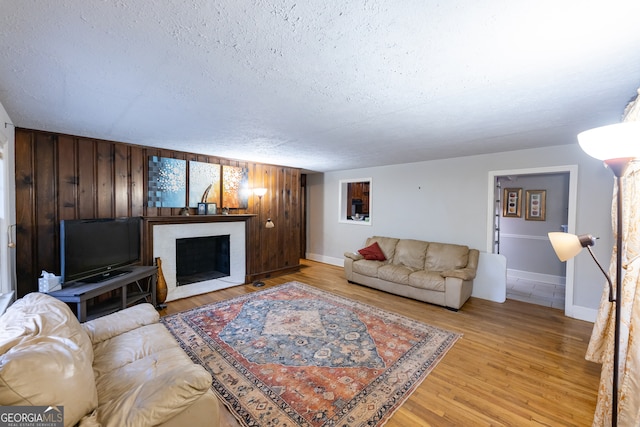 living room featuring a textured ceiling, light hardwood / wood-style flooring, and wood walls