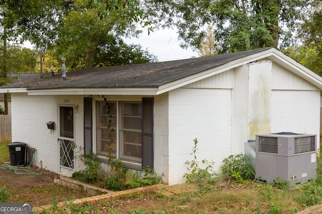 view of property exterior with cooling unit, a garage, and an outbuilding