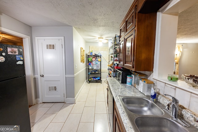 kitchen with ceiling fan, sink, black fridge, a textured ceiling, and light tile patterned floors