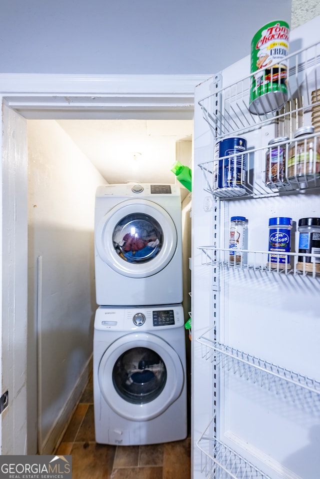 laundry area featuring dark tile patterned flooring and stacked washer / drying machine