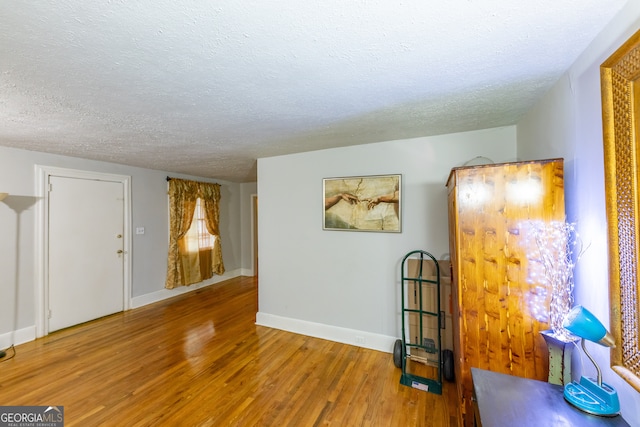 empty room with wood-type flooring and a textured ceiling