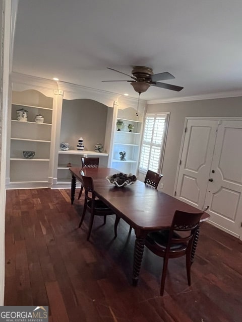 dining area featuring built in shelves, crown molding, ceiling fan, and dark wood-type flooring