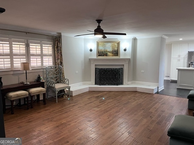 living area featuring ceiling fan, dark hardwood / wood-style flooring, and crown molding