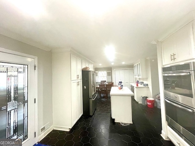 kitchen featuring white cabinets, a center island, stainless steel appliances, and dark tile patterned flooring