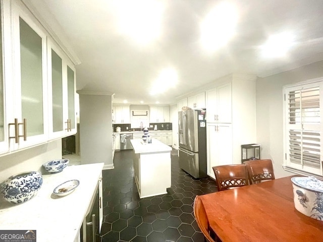 kitchen featuring white cabinetry, sink, stainless steel fridge, a kitchen island, and dark tile patterned flooring