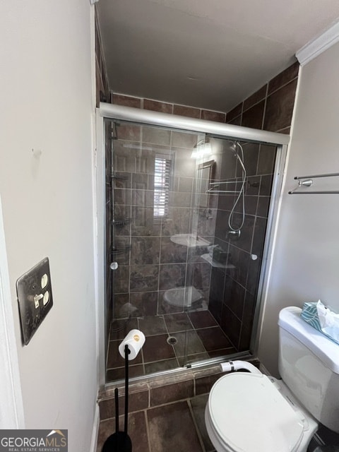 bathroom with an enclosed shower, toilet, and tile patterned floors