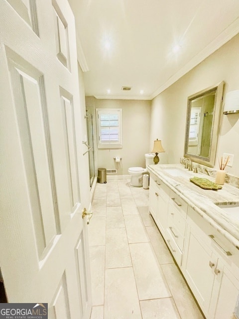 bathroom featuring tile patterned floors, crown molding, toilet, a shower with door, and vanity