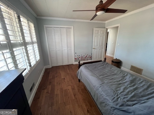 bedroom with ceiling fan, crown molding, dark wood-type flooring, and a closet