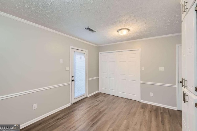 foyer entrance with ornamental molding, a textured ceiling, and hardwood / wood-style flooring