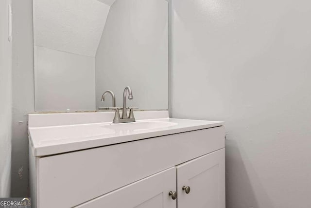 bathroom featuring vanity and lofted ceiling