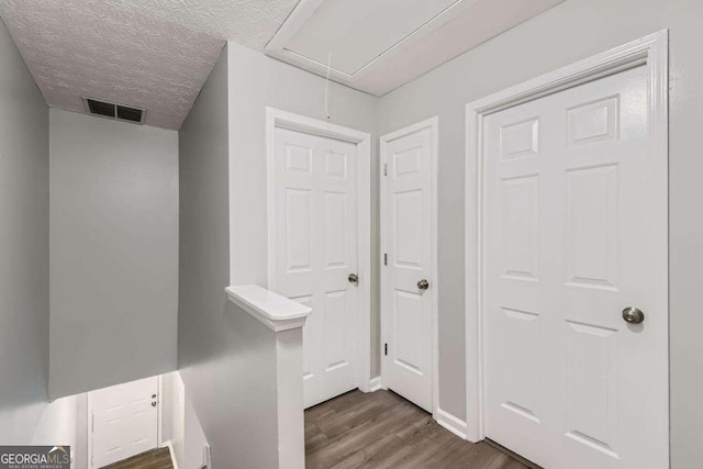 hall featuring a textured ceiling and dark hardwood / wood-style floors