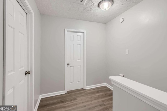 corridor featuring a textured ceiling and dark wood-type flooring