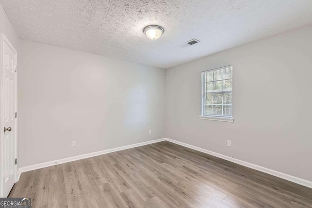 unfurnished room featuring hardwood / wood-style floors and a textured ceiling