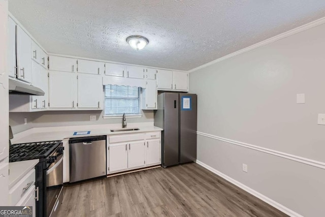 kitchen with white cabinets, appliances with stainless steel finishes, light hardwood / wood-style floors, and sink