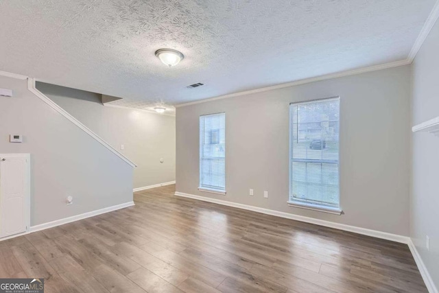 empty room with crown molding, hardwood / wood-style floors, and a textured ceiling