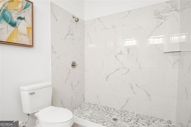 bathroom with a tile shower and toilet