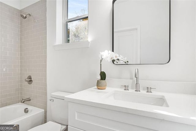 full bathroom with tiled shower / bath, vanity, and toilet