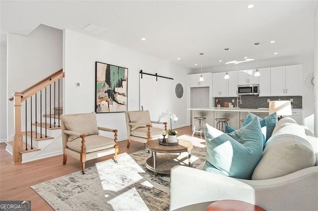 living room featuring a barn door and light hardwood / wood-style flooring