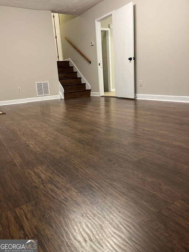 unfurnished room with a textured ceiling and dark hardwood / wood-style flooring