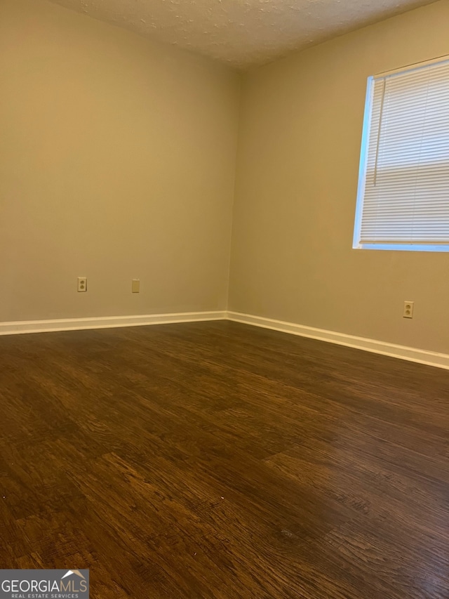 unfurnished room with dark hardwood / wood-style flooring and a textured ceiling