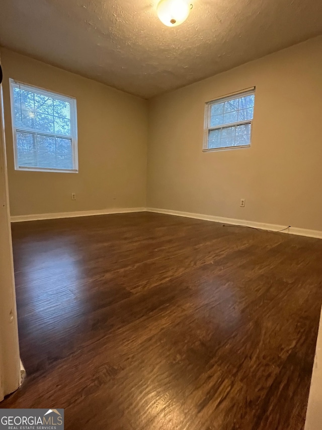 unfurnished room featuring dark hardwood / wood-style floors and a textured ceiling