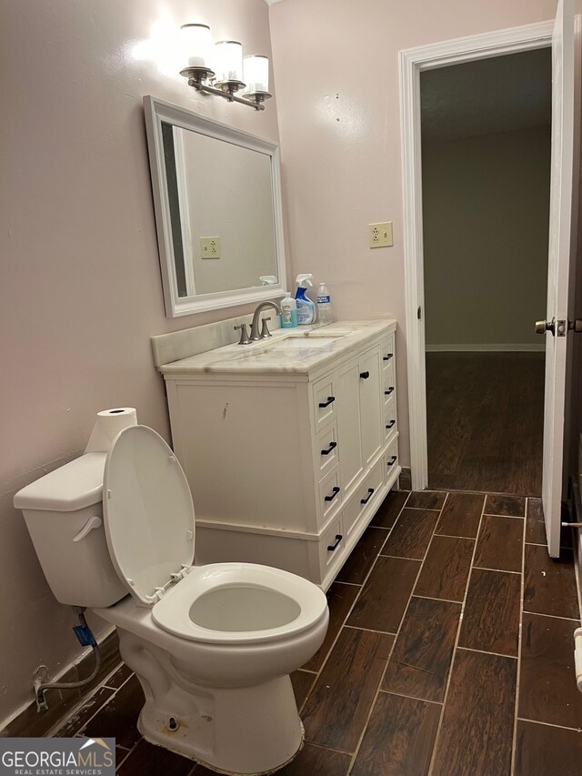 bathroom with hardwood / wood-style floors, vanity, and toilet