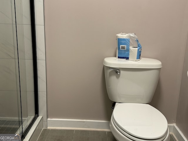 bathroom featuring toilet and a shower with door