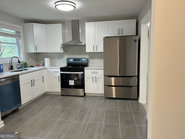 kitchen featuring tasteful backsplash, stainless steel appliances, sink, wall chimney range hood, and white cabinetry