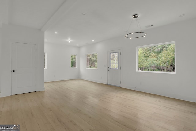 empty room featuring a chandelier and light wood-type flooring