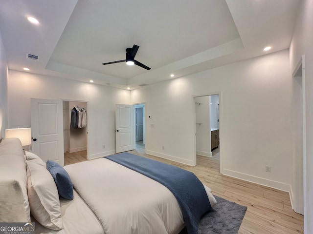 empty room featuring a raised ceiling, ceiling fan, and light hardwood / wood-style flooring