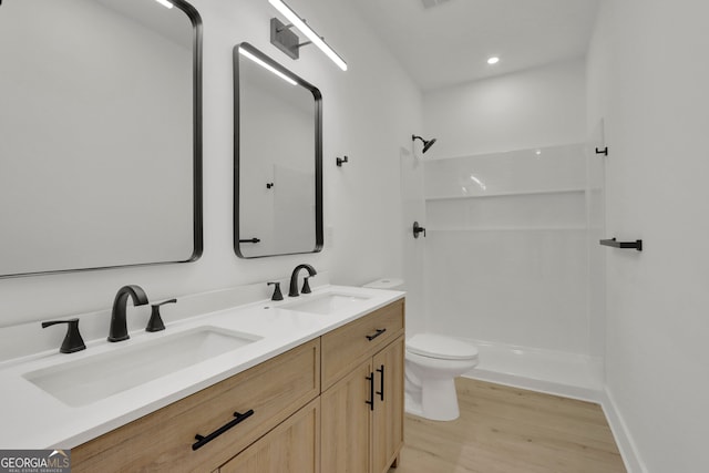 bathroom featuring hardwood / wood-style flooring, vanity, toilet, and a shower