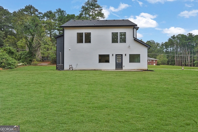 back of house with cooling unit and a lawn