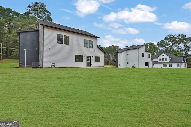 rear view of property featuring a yard and central air condition unit