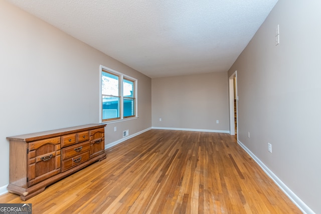 unfurnished room with a textured ceiling and light hardwood / wood-style floors