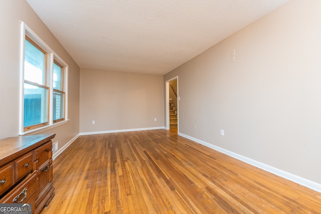 spare room with a textured ceiling and light wood-type flooring