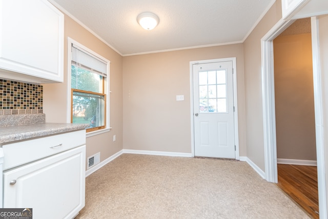 doorway to outside featuring a textured ceiling and ornamental molding