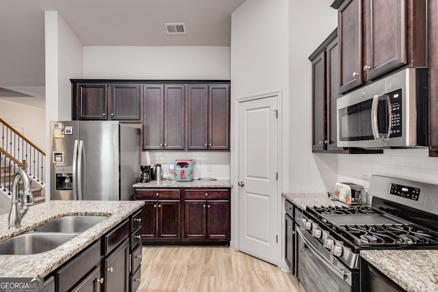 kitchen featuring light stone countertops, sink, stainless steel appliances, and light hardwood / wood-style floors