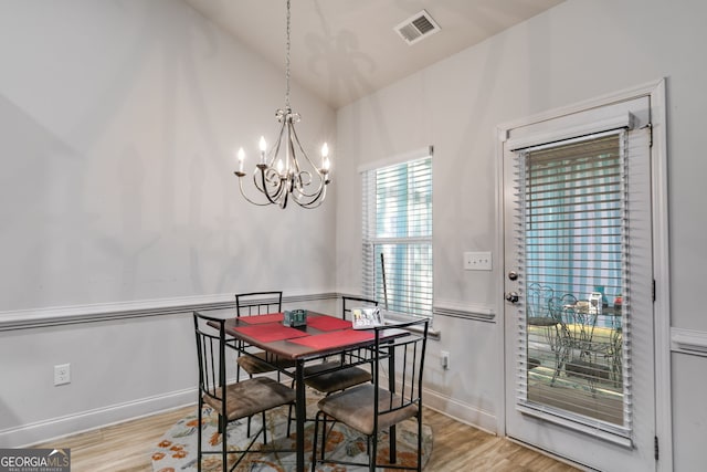 dining room with lofted ceiling, light hardwood / wood-style flooring, and a notable chandelier