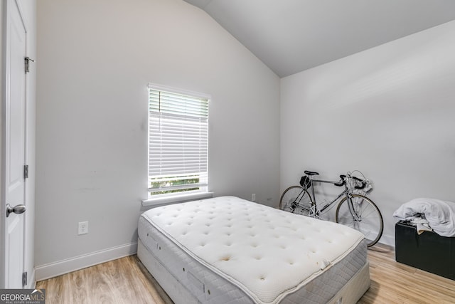 bedroom featuring light hardwood / wood-style flooring, multiple windows, and lofted ceiling