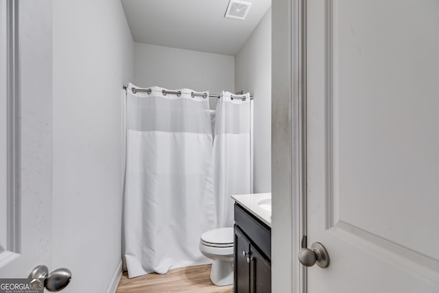 bathroom featuring walk in shower, vanity, wood-type flooring, and toilet