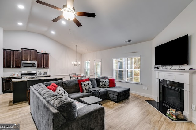 living room featuring ceiling fan with notable chandelier, light hardwood / wood-style floors, and lofted ceiling