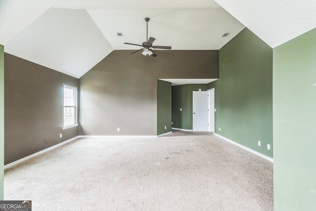 carpeted empty room featuring a textured ceiling, vaulted ceiling, and ceiling fan