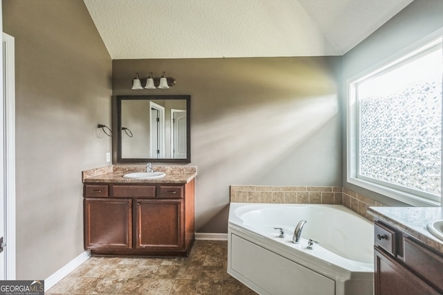 bathroom with a textured ceiling, vanity, lofted ceiling, and a bath