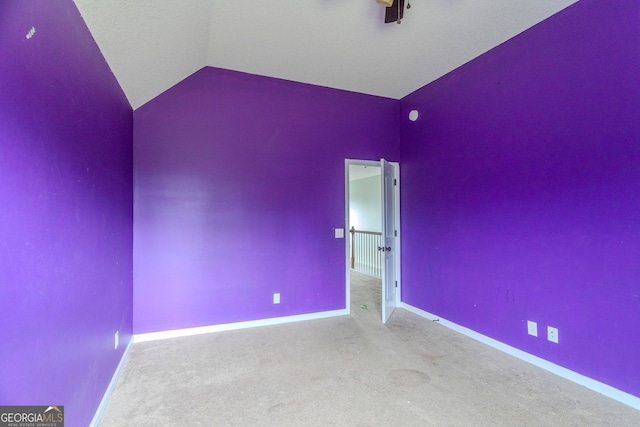 carpeted spare room with vaulted ceiling