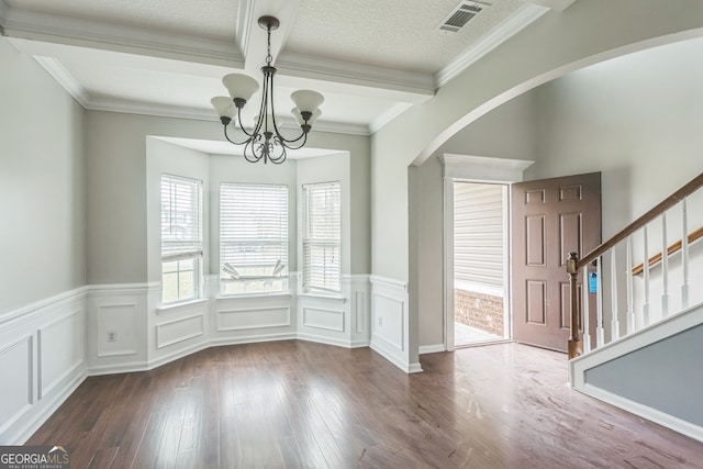 unfurnished dining area featuring hardwood / wood-style floors, ornamental molding, beamed ceiling, and a chandelier