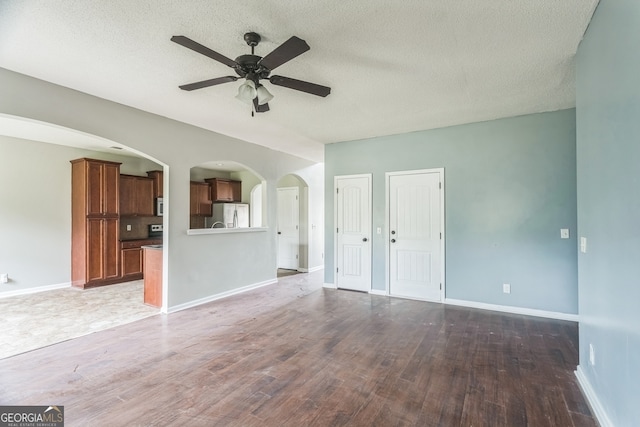 unfurnished living room with ceiling fan, dark wood-type flooring, and a textured ceiling