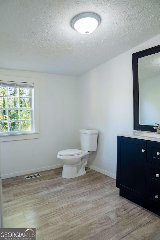 bathroom featuring hardwood / wood-style floors, vanity, toilet, and a textured ceiling