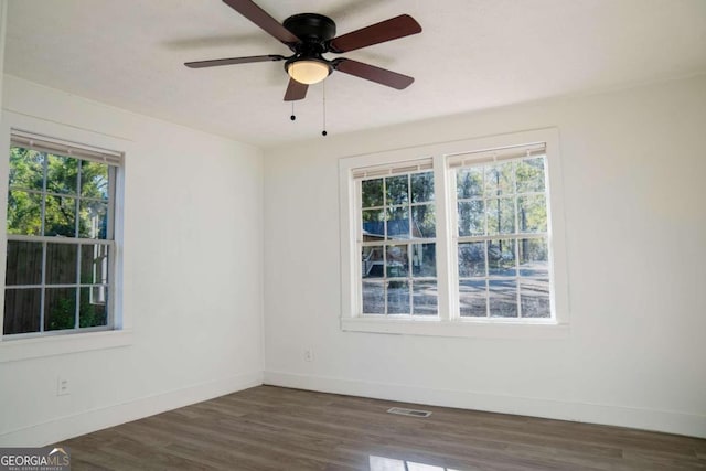 empty room featuring dark wood-type flooring, ceiling fan, and a healthy amount of sunlight