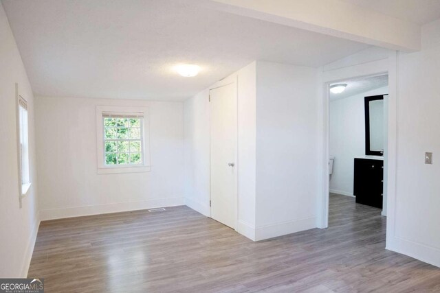 spare room with lofted ceiling and light wood-type flooring