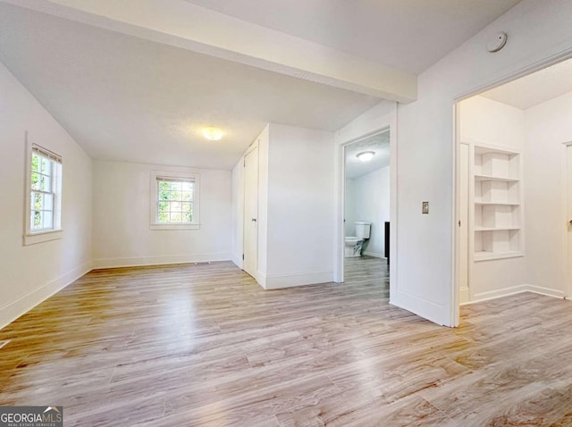 empty room with vaulted ceiling with beams and light hardwood / wood-style flooring